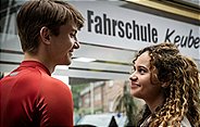 Marten Keuber (Luke Matt Rönten) ist überrascht Ela Malik (Saron Degineh) vor der Fahrschule seiner Eltern zu treffen.